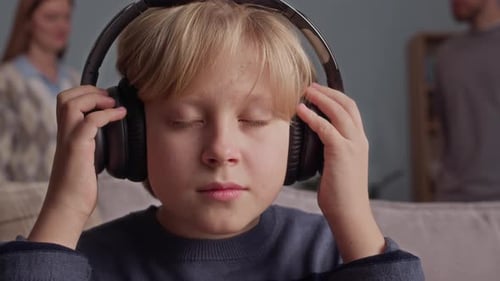 Stressed Boy Wearing Headphones while Parents Arguing in Background