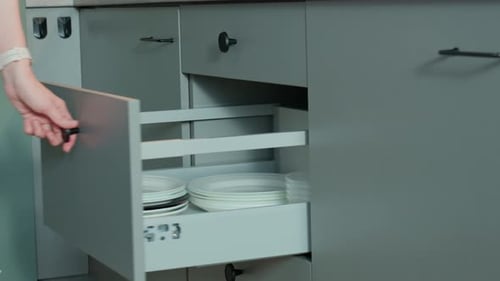 Person Opening Kitchen Drawer with Cutlery in Cabinet