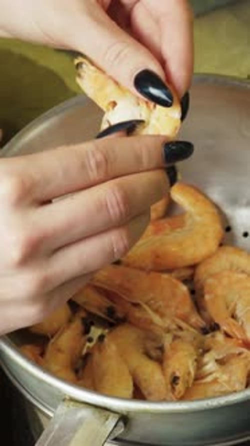 Girl cleans big boiled shrimp close up Vertical video.