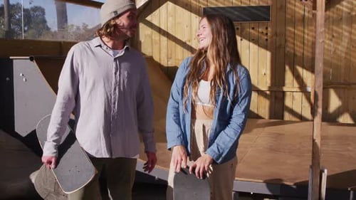 Video of happy caucasian female and male skateboarders in skate park