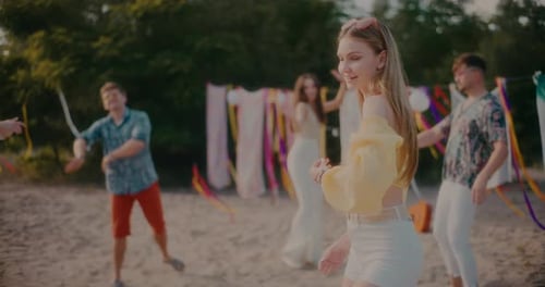 Belle femme dansant contre des amis sur la plage