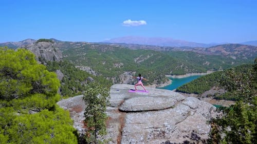 Woman Practicing Yoga on Cliff with Panoramic Mountain and Lake View