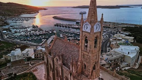 Aerial view of Malta's harbor at sunset with historic buildings