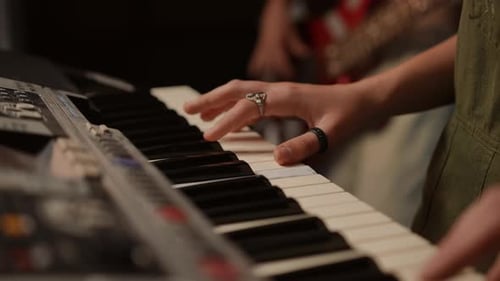Closeup During a Rehearsal at a Music School a Teacher and a Student Play a Fourhanded Synthesizer