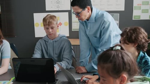 Students Working on Laptops with Teacher in Classroom