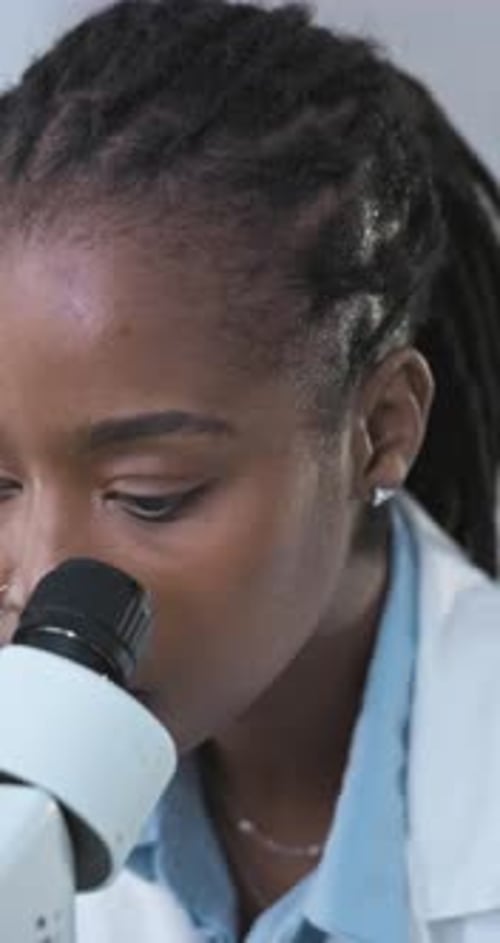 Female Scientist Looking Into a Microscope in Lab