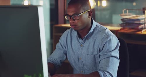 4k video footage of a young businessman looking stressed out while working late in an office