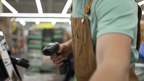 Construction Worker Uses a Handheld Barcode Scanner to Scan a Roll of Packaging Tape and His Credit