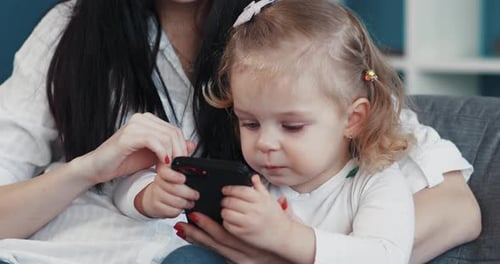Mother and Child Watching a Smartphone on Couch