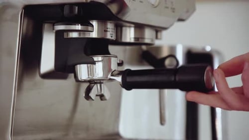 Young male grinding coffee ground into portafilter at home for espresso. Home Barista Close Up Hand