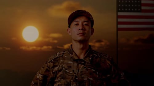 Uniformed Soldier Stands Before an American Flag at Sunrise