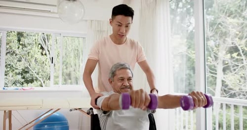 Senior Exercising with Assistant Using Weights Indoors