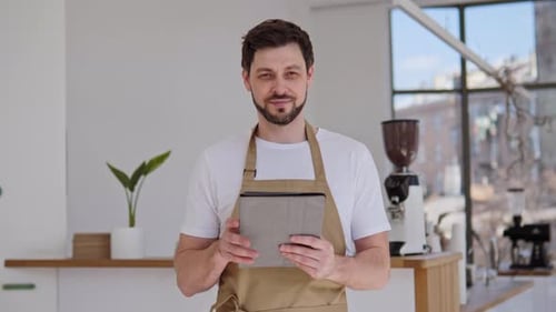 Smiling Man Holding Tablet in Bright Cafe