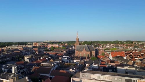 Drone view of a picturesque European town with a towering church, red-roofed houses, winding