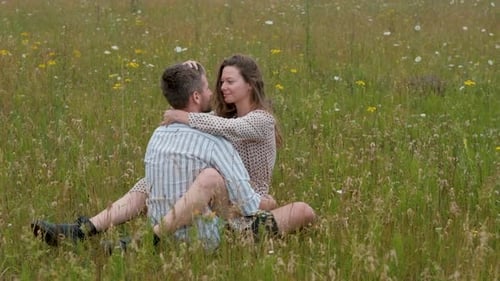 Young Couple Enjoying Each Other in the Middle of Field Outdoors Woman Sitting on the Man and