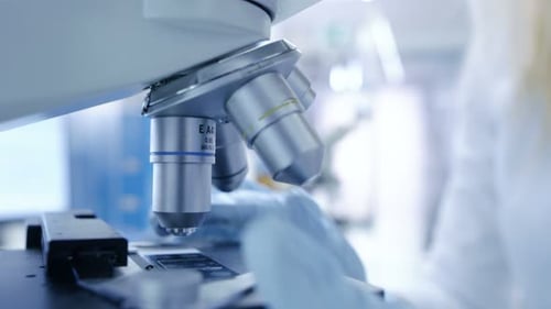 Medical Research Scientists Puts Slides in Place and Looking at Samples Under Microscope. She Works