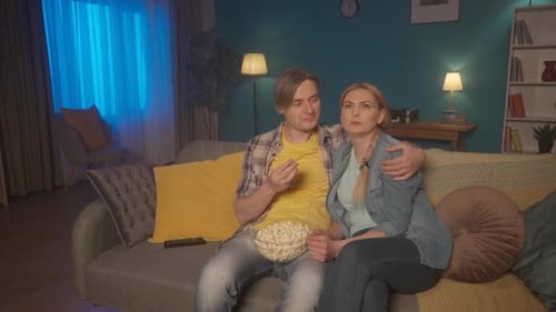 A Married Couple Sits Hugging on the Couch with a Plate of Popcorn and Watching a Movie A Man and a