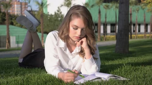 Beautiful Female Student Reads a Book in the Park