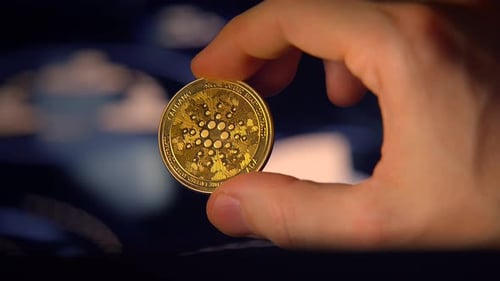 Uma mão segurando uma moeda de criptomoeda dourada brilhante que simboliza a riqueza digital e o sucesso futuro