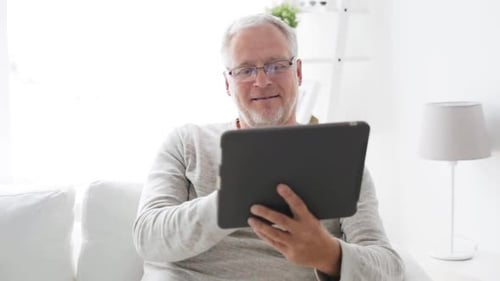 Senior man using tablet computer in living room