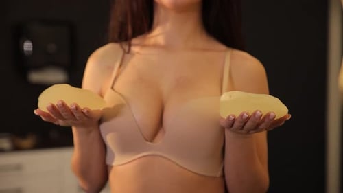 Woman Holding Silicone Breast Implants Indoors