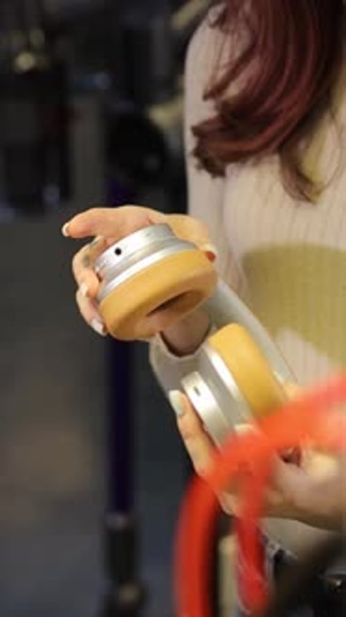 The Girl Chooses Headphones in the Store Gadgets for Listening to Music