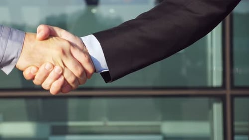 Businessmen Handshake Agreement in front of Corporate Building