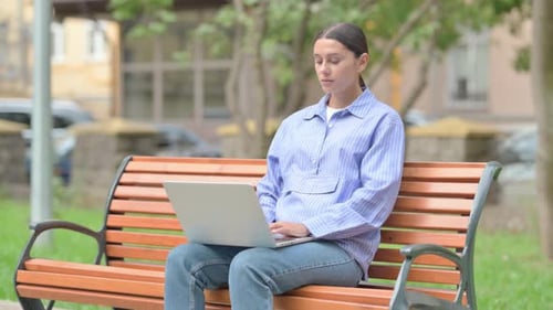 Woman Works on Laptop in Urban Park