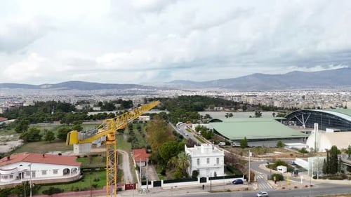 Luftaufnahme neben einem hoch aufragenden Baukran. Über einer Baustelle fliegen 4K