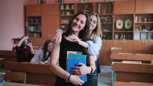 Female Students Smiling and Embracing in Classroom