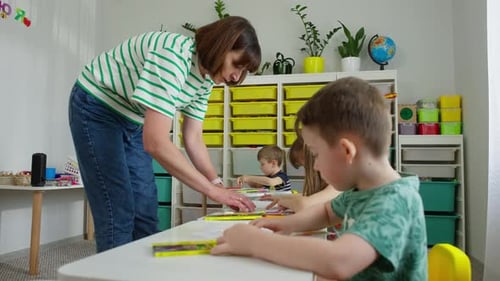 Teacher Assists Children with Art Project in Classroom