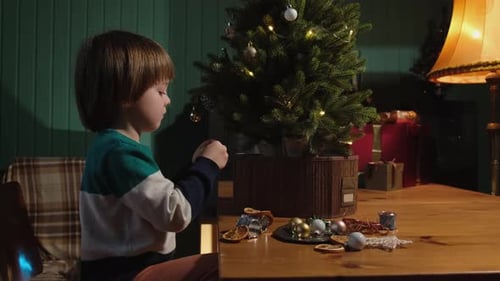 Boy Decorates Christmas Tree with Festive Ornaments