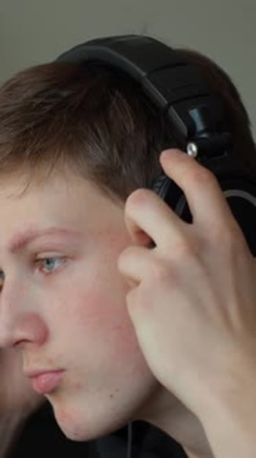 Young Man Adjusting Headphones Indoors in Vertical Video
