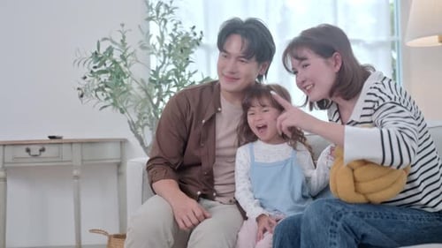 La familia disfruta del tiempo juntos mientras comparten sonrisas y risas en la luminosa sala de estar