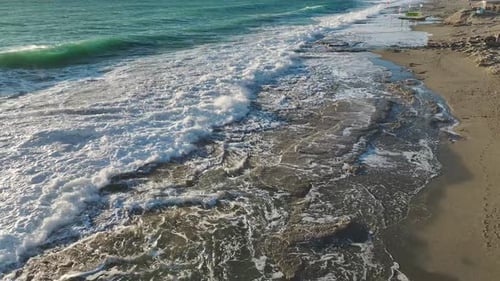 Waves Crashing on Sandy Beach from Above