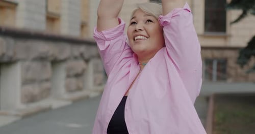 Slow Motion of Active Asian Girl Listening to Music Through Headphones and Dancing Outside in City