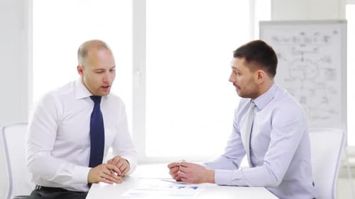 Business, Partnership, Finances and Office Concept - Two Smiling Businessmen Holding Papers