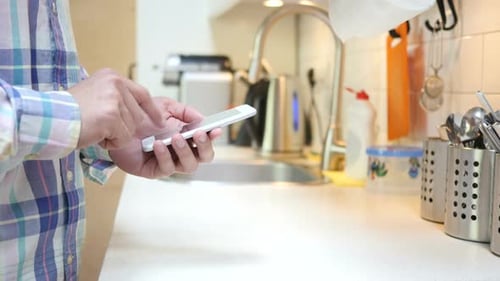 Adult Uses Smartphone Device in Kitchen