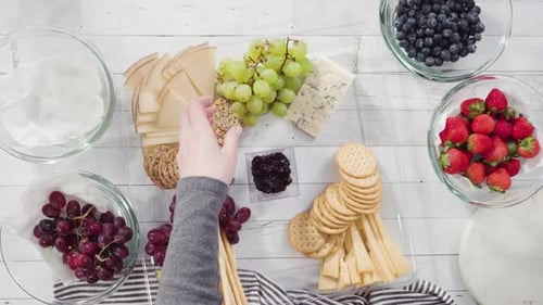 Arranging Gourmet Cheese Board with Fruit and Crackers