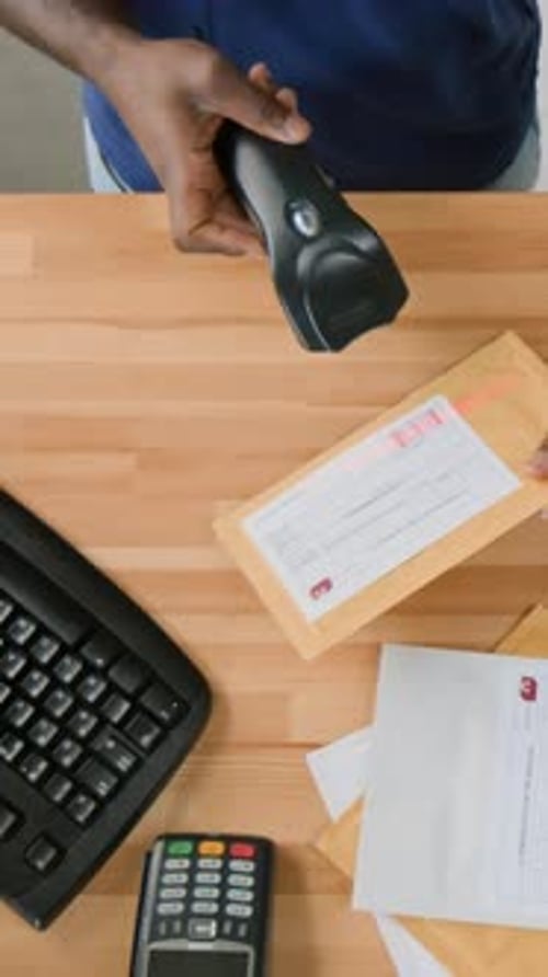 Vista superior vertical de um operador masculino anônimo digitalizando códigos de barras em pacotes