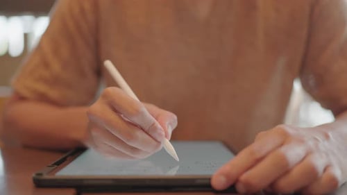 Man looking at digital tablet screen while sitting in modern coffee shop