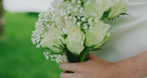 Close Up of Bride in Her Lace Wedding Gown Holding Bouquet of White Roses and Greenery in Her Hands