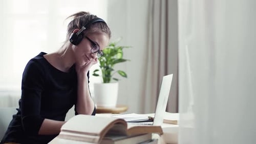 Young woman studying at home with headphones for college exam preparation
