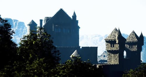 Historic Castle Silhouette Against Misty Mountains During Early Morning