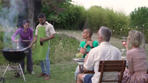 Friends Enjoying Outdoor Barbecue in a Green Garden