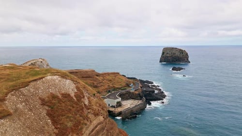 Costa rochosa que estende a água do mar com vista de drone, encostas de montanhas banhadas pelo oceano azul