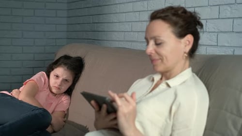 Woman Using Tablet as Child Sits Angrily