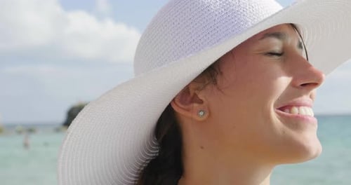 Portrait of a beautiful young girl (woman) at the sea in a swimsuit, white hat, smiling, sea and s