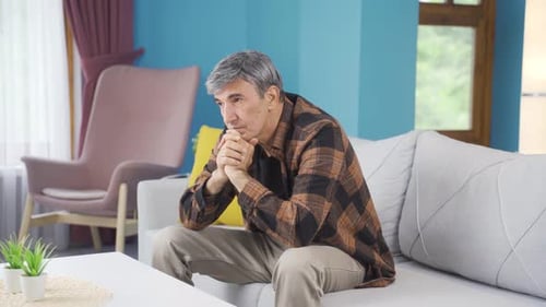 Man Sitting Contemplatively on Couch Indoors