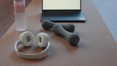 Workout Equipment on Yoga Mat Next to Laptop